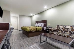 a hotel room with a bed and a couch at Scottish Inn and Suites Tomball in Tomball