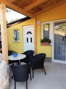 a patio with a table and chairs and a white door at Apartmani Ljerka Malinska in Malinska