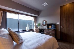 um quarto com uma cama, uma secretária e uma televisão em R&Run Kyoto Serviced Apartment & Suites em Quioto