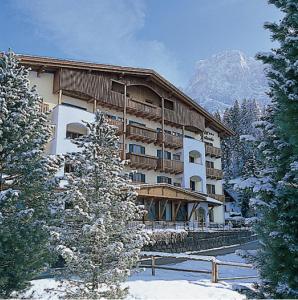 un grand bâtiment dans la neige avec une montagne dans l'établissement Hotel Jolanda, à San Martino di Castrozza