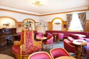 a restaurant with purple chairs and tables and a bar at Hotel Jolanda in San Martino di Castrozza