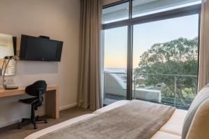 a hotel room with a bed and a desk and a window at Head South Lodge in Cape Town