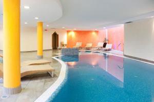 a hotel lobby with a swimming pool and chairs at Hotel Jolanda in San Martino di Castrozza