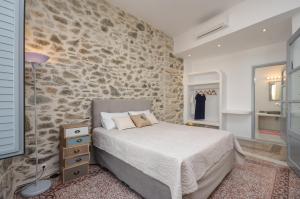 1 dormitorio con cama y pared de piedra en Naxos Center Houses, en Naxos Chora