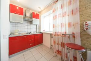 a small kitchen with red cabinets and a red stool at Partner Guest House Saksahans'koho in Kyiv