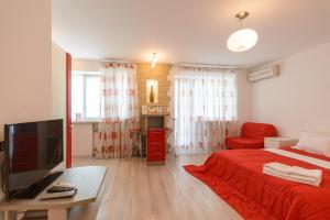 a living room with a red bed and a television at Partner Guest House Saksahans'koho in Kyiv