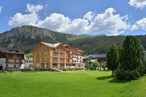 a large building in a field with mountains in the background at Hotel Spol - Adults only in Livigno