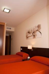 1 Schlafzimmer mit 2 Betten mit orangefarbener Bettwäsche und einer Lampe in der Unterkunft Hostal Granado in Madrid