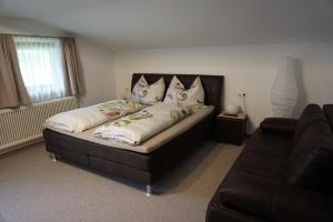 1 dormitorio con cama con almohadas y sofá en Habachschmied Familie Gruber, en Bramberg am Wildkogel