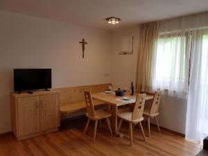 a dining room with a table with chairs and a tv at Ferienwohnungen Schlosshäusl in San Lorenzo di Sebato