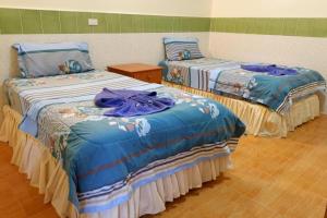 two beds in a room with blue comforters at Harmony House-SHA Plus in Phi Phi Islands