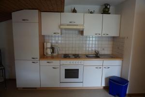 a small kitchen with white cabinets and a sink at Habachschmied Familie Gruber in Bramberg am Wildkogel
