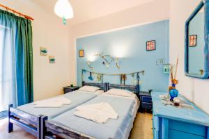 a blue bedroom with two beds and a mirror at Apokoros Craft Deco Apartments&Studios in Kalyves