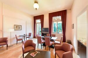 a living room with tables and chairs and a television at Waldhotel Unspunnen in Interlaken