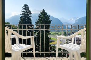 2 sillas blancas en un balcón con vistas a las montañas en Waldhotel Unspunnen, en Interlaken