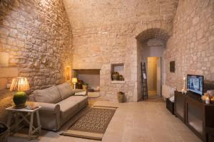 Una sala de estar con un sofá y una pared de piedra. en Masseria Le Cerase, en Conversano