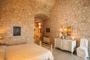 a bedroom with a bed and a dresser in a stone wall at Masseria Le Cerase in Conversano