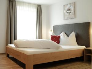 a bedroom with a bed with white sheets and red pillows at Pension Apartment Erna in Resia