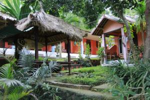 a house with a thatch roof and a table in a garden at Roy Homestay in Kuta Lombok