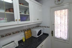 una cocina con armarios blancos y microondas en una encimera en Maryvilla 224, en Calpe