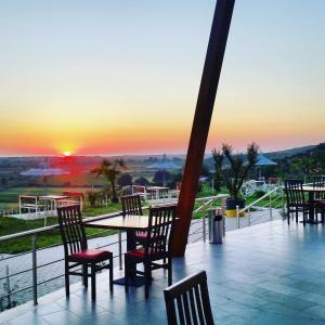 a patio with chairs and a table with a sunset in the background at Hotel Restorant Panorama in (( Bashtovë ))