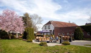 eine Gruppe von Personen, die vor einem Gebäude an Tischen sitzen in der Unterkunft Hotel Restaurant Eeserhof in Ees