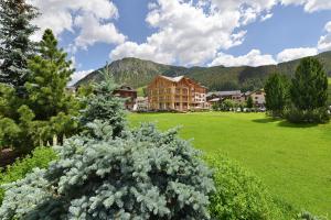 um grande campo verde com um edifício ao fundo em Hotel Spol - Adults only em Livigno