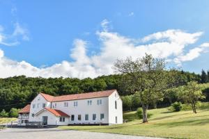 een wit huis op een grasheuvel met bomen bij GT3 Hotel in Honerath