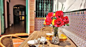 un vase de fleurs rouges sur une table en bois dans l'établissement Villa Carabeo, à Nerja