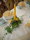 uma mesa com uma vela amarela e flores sobre ela em Berghof Lichtenhain em Lichtenhain