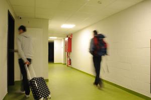 
a man walking down a hallway with an open suitcase at Hostel Bruegel in Brussels
