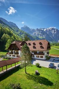 a large building with mountains in the background at Hotel Plesnik Logarska Dolina in Solčava