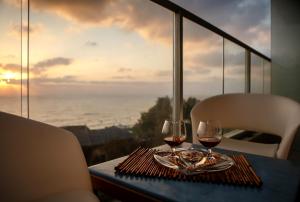 two glasses of wine on a table with a view of the ocean at Medi Terre Boutique Hotel - By Saida Hotels in Netanya