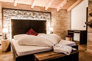 a bedroom with a large bed and a wooden wall at Garni Residence Soraiser in Selva di Val Gardena