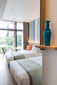 a hotel room with three beds and a vase on a shelf at JR Kyushu Hotel Blossom Naha in Naha