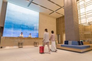 duas pessoas a andar num átrio do aeroporto com a sua bagagem em JR Kyushu Hotel Blossom Naha em Naha