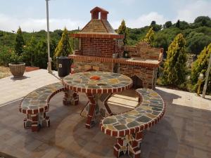 a patio with a table and chairs and a brick grill at Alexia Ferentinou in Fiskardho