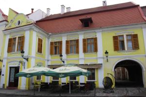 um edifício amarelo com dois guarda-chuvas à frente em Ferdinand Apartments em Mediaş