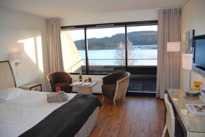 Farsund Fjordhotel في فارسوند: غرفة فندقية بسرير ونافذة كبيرة