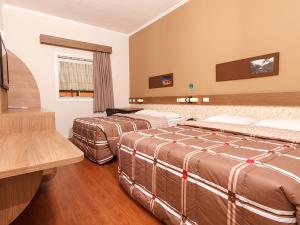 a hotel room with two beds and a television at Hotel 10 Uniao da Vitoria in União da Vitória