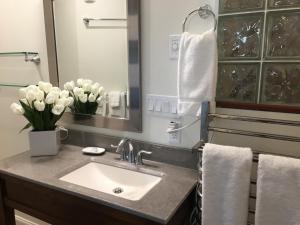 a bathroom with a sink and a mirror and flowers at Camden Riverhouse Hotel and Inn in Camden +38 photos