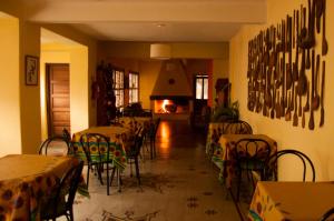 comedor con mesas y sillas y chimenea en Hostería La Pergola en Villa Serranita
