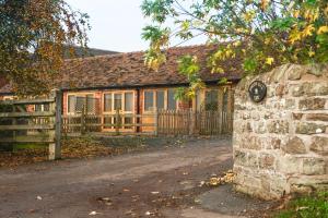 uma casa com uma cerca e uma parede de pedra em Cart Shed Cottage em Newport