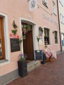 un edificio rosa con una mesa delante en Weinstube Heigl Restaurante Pizzeria Puccini, en Landshut