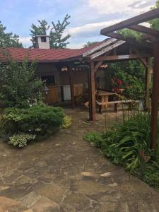 a garden with a wooden pergola in front of a house at Davidkov Holiday Home in Shipka