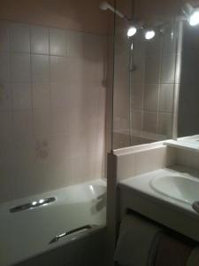 y baño con bañera, lavamanos y ducha. en Hôtel des Voyageurs, en Saint-Chély-dʼAubrac
