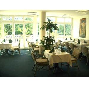 - une salle à manger avec des tables, des chaises et des fenêtres dans l'établissement Hotel Kubrat an der Spree, à Berlin