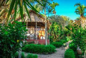 una casa en medio de un jardín con árboles en Coucher de Soleil en Ambatoloaka