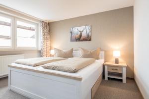 Un dormitorio con una cama blanca con una foto de ciervo en la pared en Ferienhof Heins en Undeloh