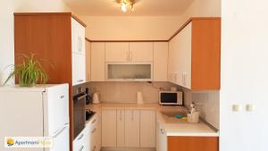 a kitchen with white cabinets and a white refrigerator at Apartman Hana in Ika